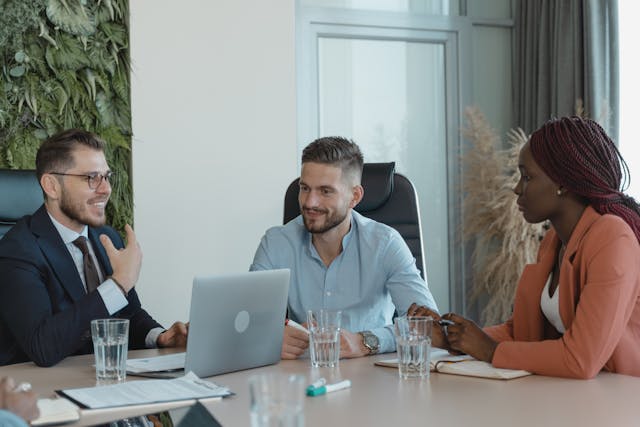 three people sitting in a conference room having a meeting